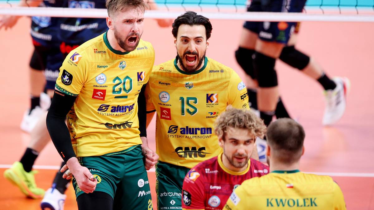 Dw&oacute;ch siatkarzy w ż&oacute;łtych koszulkach z numerami 20 i 15 świętuje zdobycie punktu, w tle inni zawodnicy.