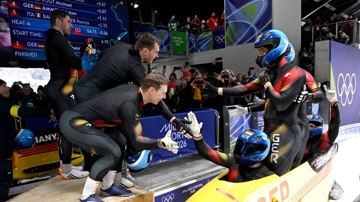 Drużyna Niemiec w strojach bobslejowych świętuje zwycięstwo, podając sobie ręce.