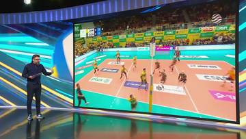 Mężczyzna analizuje mecz siatkówki wyświetlany na dużym ekranie.