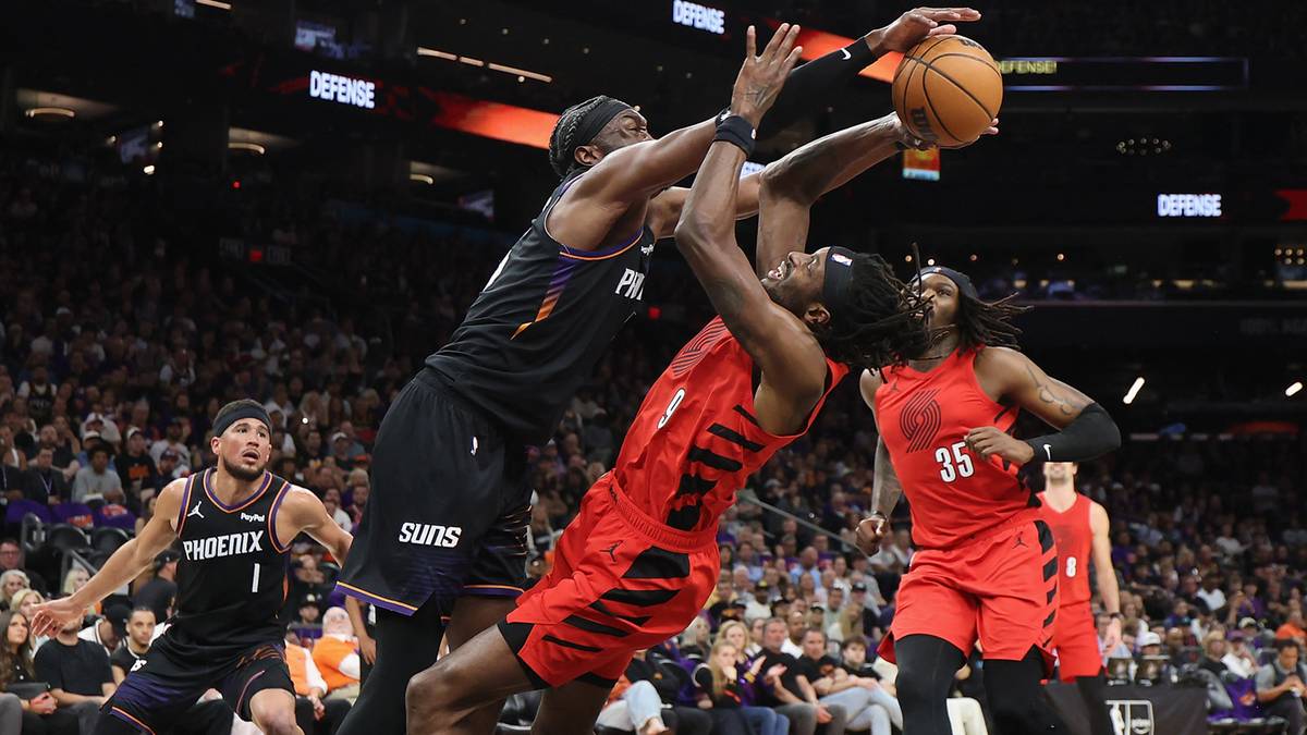 Gracze koszykówki w akcji podczas meczu, jeden z nich rzuca do kosza.