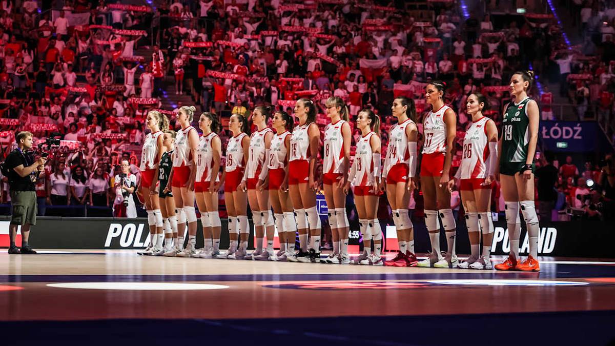 Siatkarki reprezentacji Polski stoją w rzędzie na parkiecie, przed trybunami wypełnionymi kibicami.