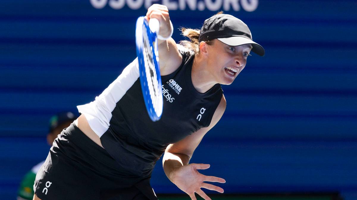 Iga Świątek podczas meczu, wykonująca uderzenie rakietą tenisową.