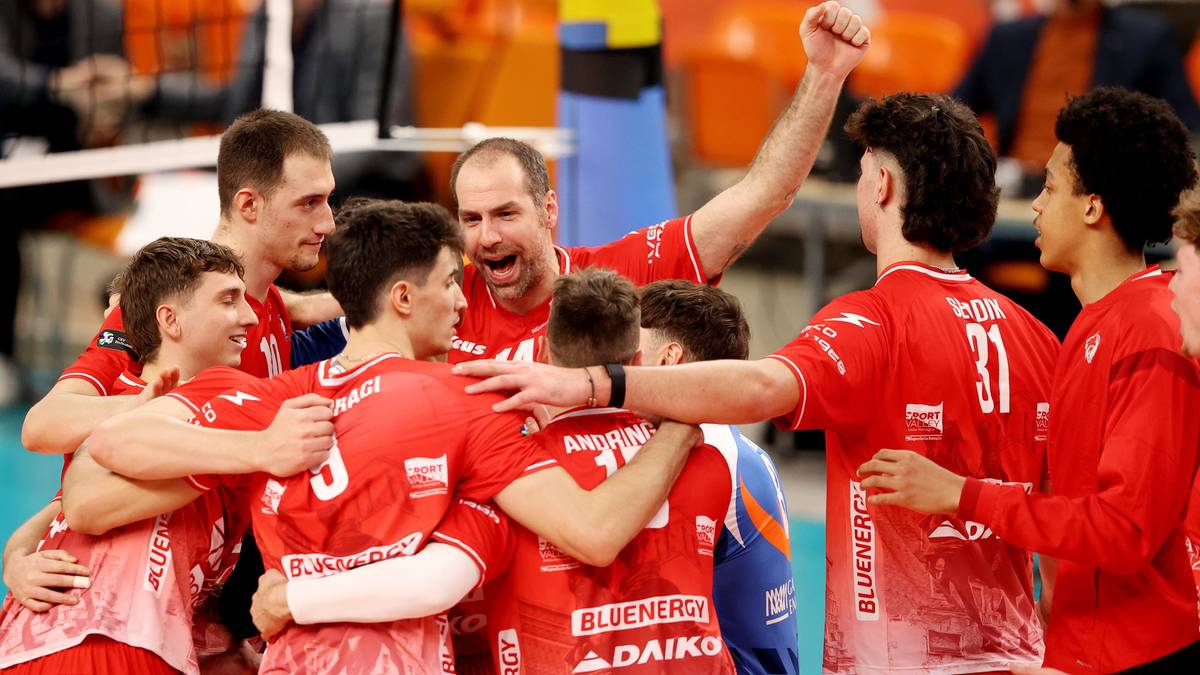 Grupa siatkarzy w czerwonych strojach świętuje zwycięstwo.