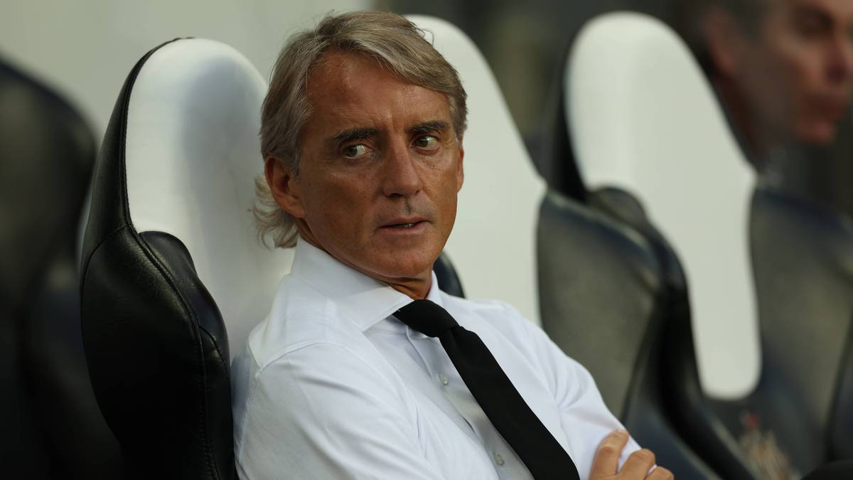 Roberto Mancini, trener piłkarski, siedzi na krześle w białej koszuli i czarnym krawacie.