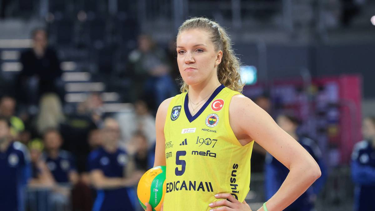 Siatkarka w żółtej koszulce z numerem 5 trzyma piłkę do siatkówki.