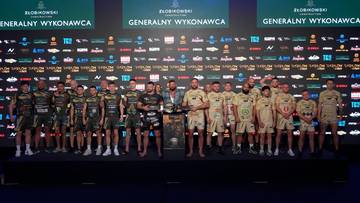 Grupa zawodników i organizatorów stoi na scenie w ramach ceremonii ważenia przed galą Babilon MMA 57. Na tle znajduje się ściana z logotypami sponsorów.