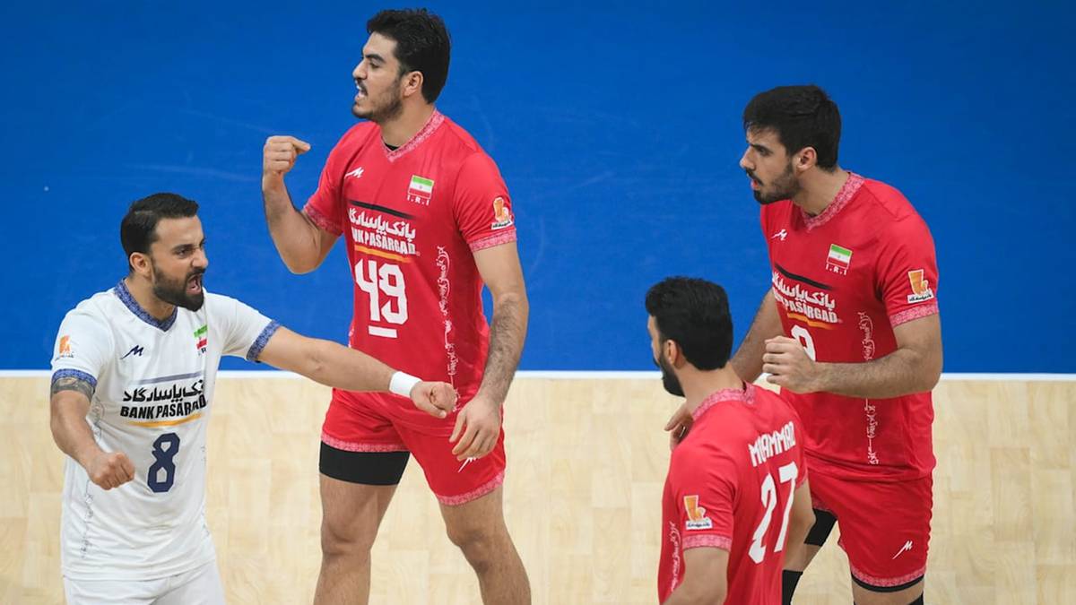 Czterech mężczyzn w strojach sportowych podczas meczu piłki ręcznej. Dwóch w czerwonych koszulkach z numerami 49 i 17 oraz dwóch w białej koszulce z numerem 8 i czerwonej.