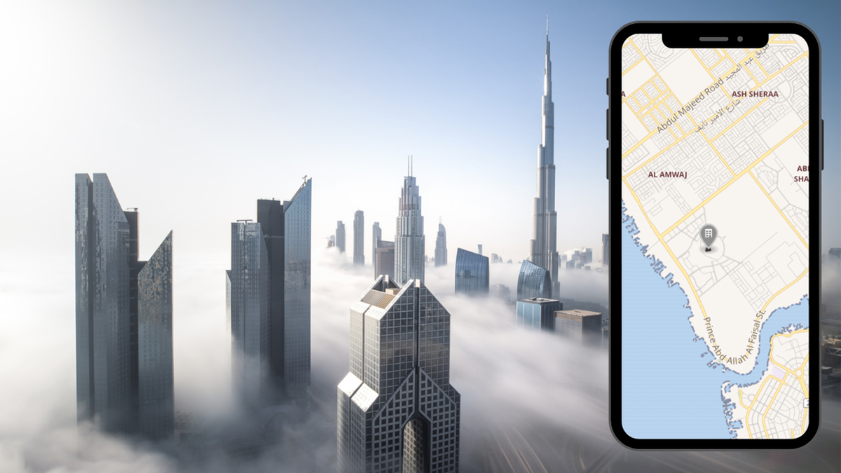 Nowoczesne drapacze chmur w mglistym krajobrazie, obok smartfon z mapą.