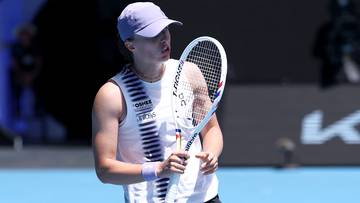 Kobieta w czapce z daszkiem i stroju tenisowym trzyma rakietę tenisową.