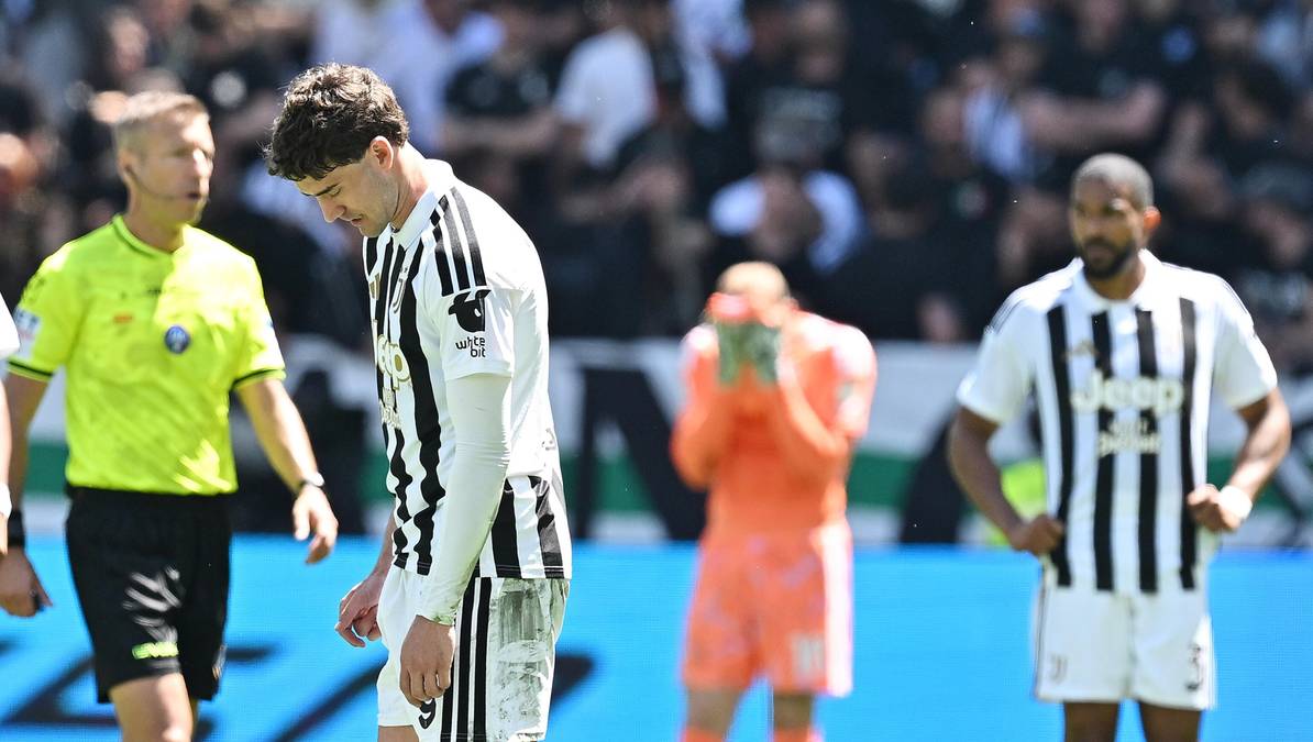 Dw&oacute;ch piłkarzy Juventusu, sędzia i bramkarz na boisku piłkarskim.