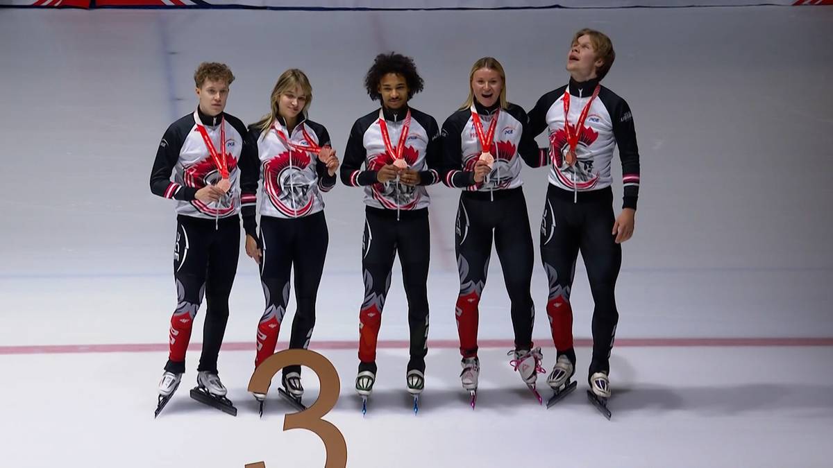 Pięcioro młodych łyżwiarzy w strojach sportowych, każdy z medalem na szyi, stoi na lodowisku.