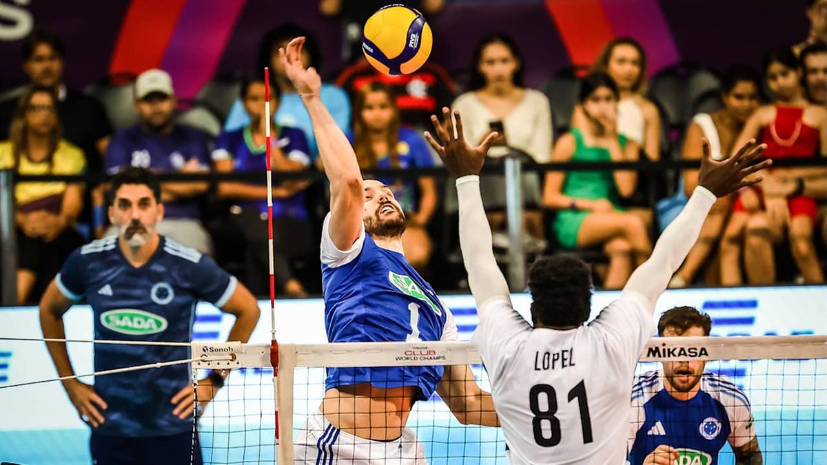 Siatkarz w niebieskim stroju odbija piłkę nad siatką, podczas gdy siatkarz w białym stroju z numerem 81 próbuje go zablokować.