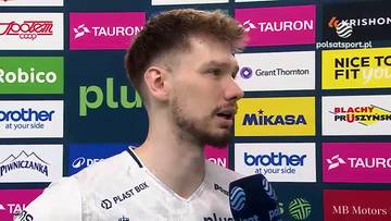 Portret Jakuba Kochanowskiego, siatkarza, z mikrofonem w tle logotyp&oacute;w sponsor&oacute;w.