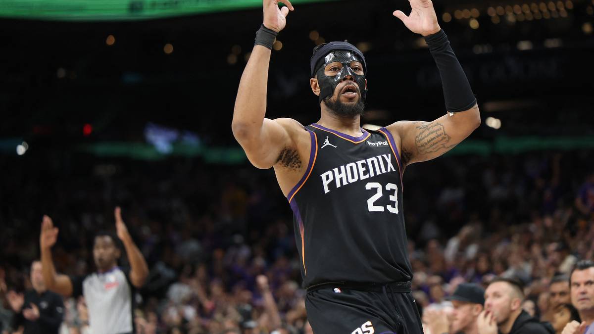 Gracz koszyk&oacute;wki w czarnej koszulce z numerem 23 i napisem PHOENIX, unosi ręce w geście triumfu.