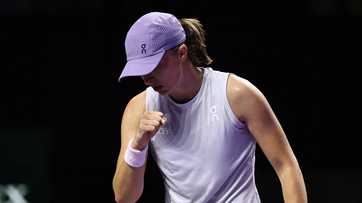 Iga Świątek, polska tenisistka, w białej koszulce i fioletowej czapce, zaciśniętą pięścią świętuje punkt na korcie tenisowym.