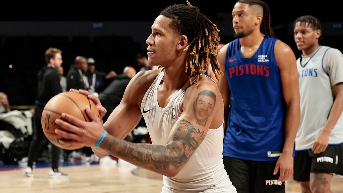 Koszykarz z piłką do koszyk&oacute;wki w rękach, w tle inni zawodnicy.