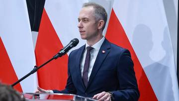 Poseł Konfederacji Stanisław Tyszka przemawia za mównicą z mikrofonem, w tle flagi Polski.