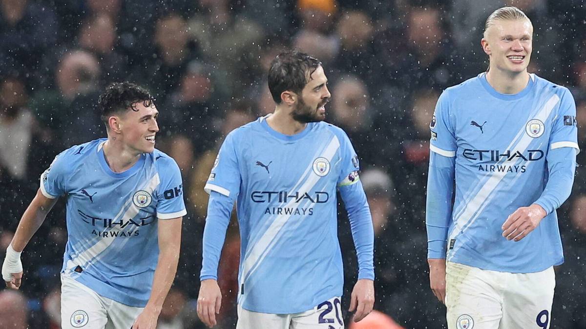Trzej piłkarze Manchesteru City w jasnoniebieskich strojach stoją na boisku.