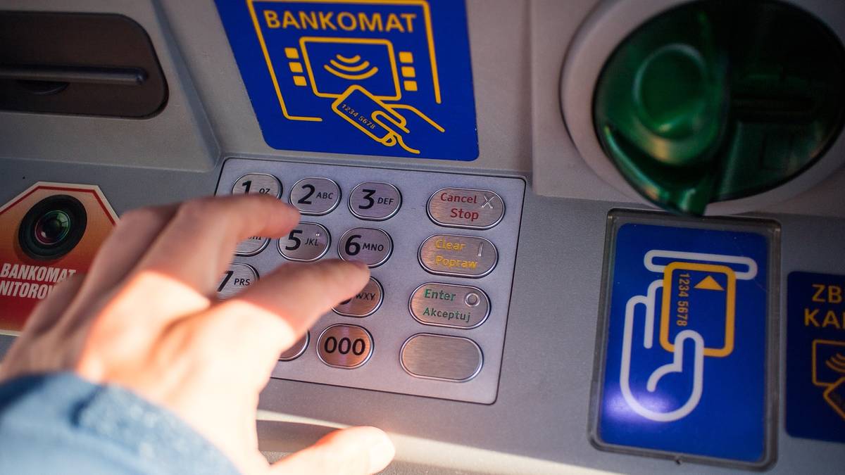 Dłoń użytkownika wpisująca PIN na klawiaturze bankomatu.