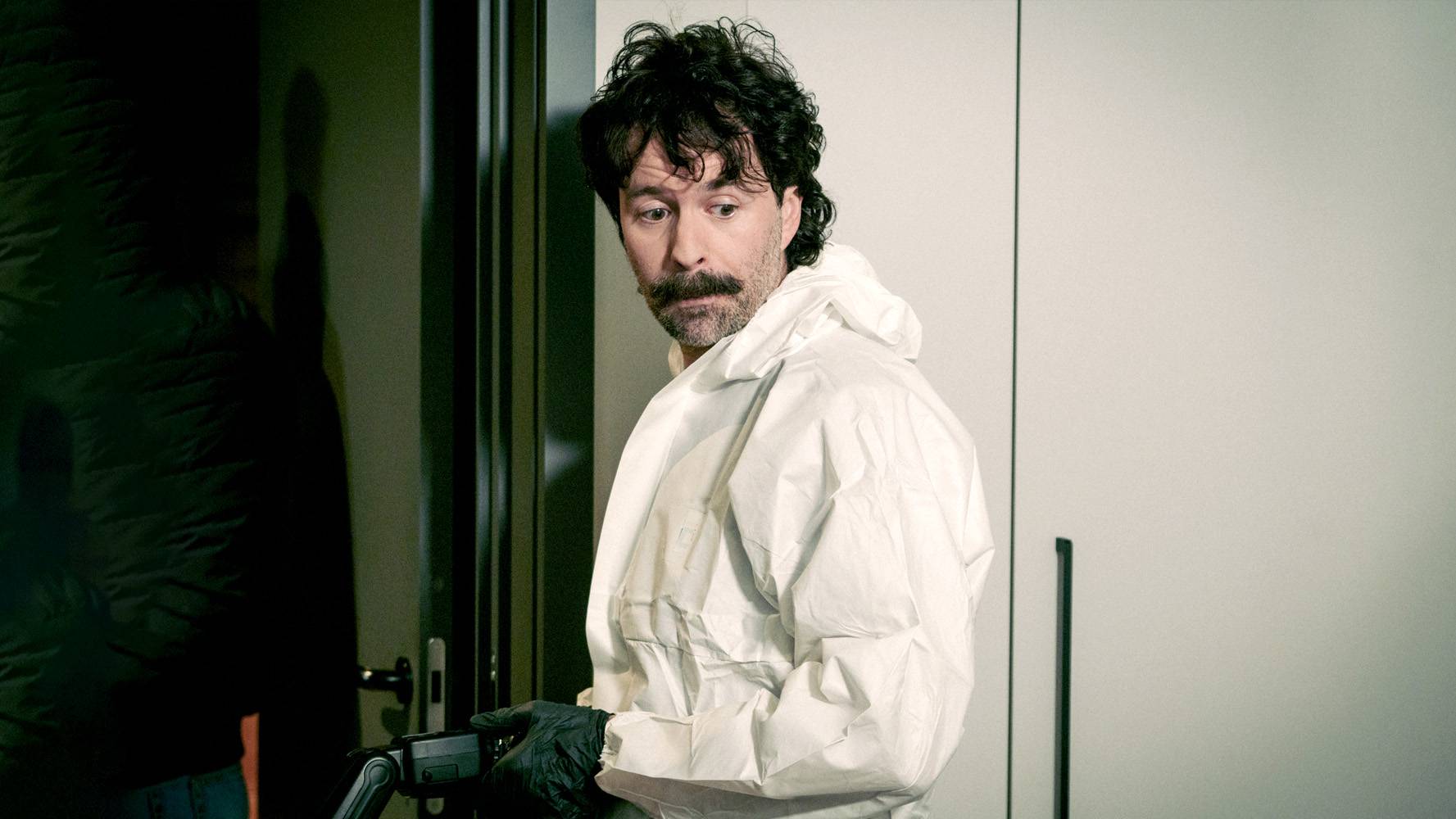 Piotr Mróz jako Roguz w białym kombinezonie i czarnych rękawiczkach