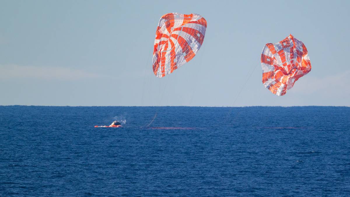Dwa spadochrony statku kosmicznego Orion unoszą się nad oceanem, przygotowując się do wodowania.