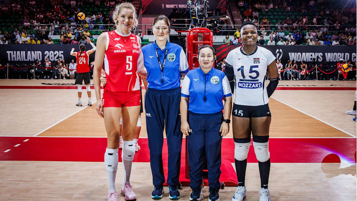 Cztery kobiety pozują do zdjęcia na boisku siatkówki. Dwie z nich to siatkarki w strojach sportowych, a dwie pozostałe to sędziny w niebieskich strojach służbowych.