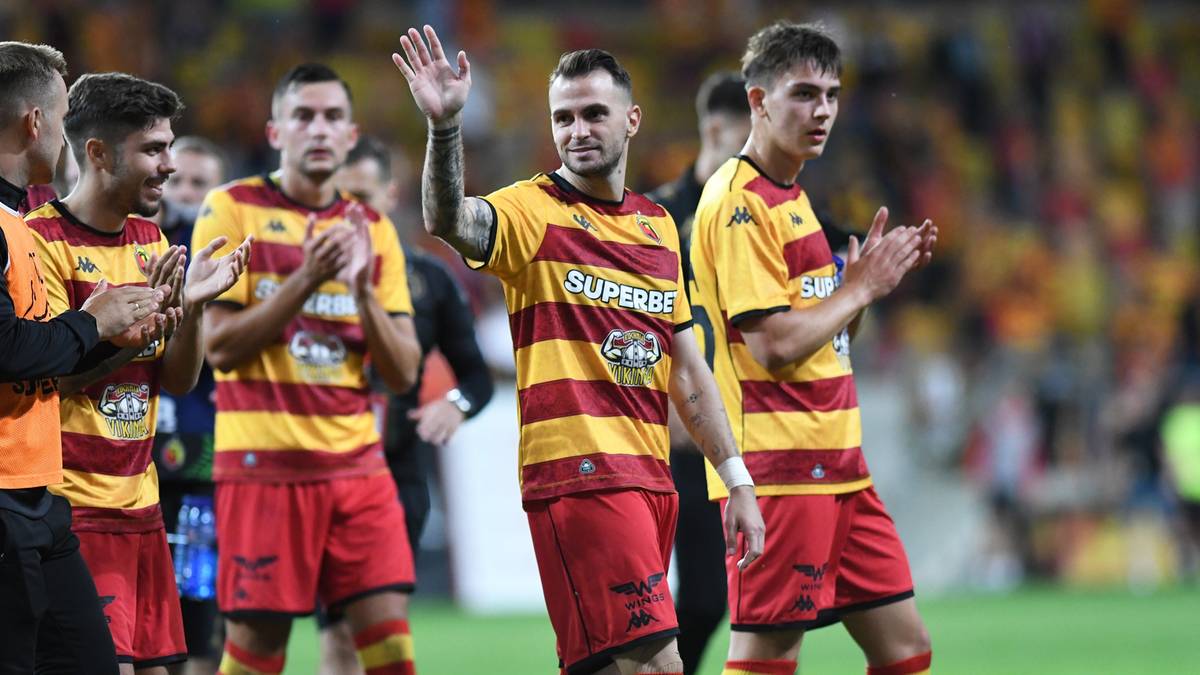 Piłkarze Jagiellonii Białystok w czerwono-żółtych strojach podczas meczu.