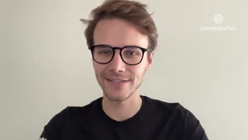 Młody mężczyzna w okularach i czarnej koszulce uśmiecha się do kamery.