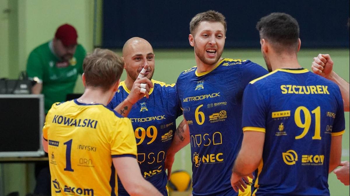 Siatkarze w strojach sportowych pozdrawiają się na boisku.