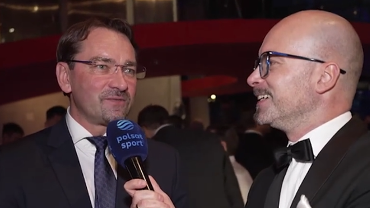 Sebastian Świderski w garniturze i krawacie udziela wywiadu mężczyźnie w garniturze i muszce, który trzyma mikrofon z logo Polsat Sport.