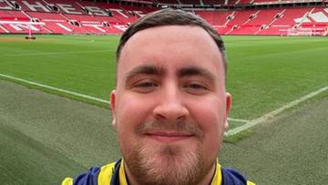 Mężczyzna w kurtce sportowej z logo Sky Sports na tle stadionu piłkarskiego.