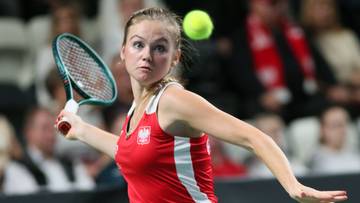 Tenisistka w biało-czerwonym stroju odbija piłkę rakietą.