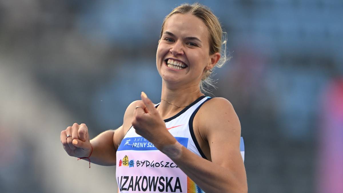 Uśmiechnięta kobieta lekkoatletka w stroju sportowym, pokazująca kciuk w g&oacute;rę.