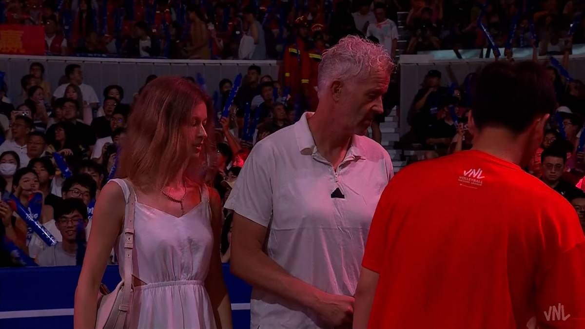 Vital Heynen rozmawia z kobietą i mężczyzną na tle trybun wypełnionych publicznością podczas meczu.