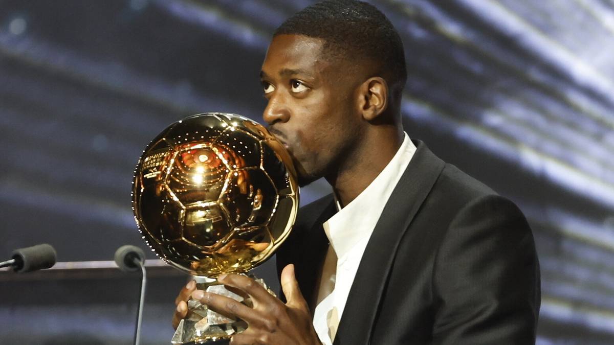 Piłkarz Ousmane Dembele całuje złotą statuetkę w kształcie piłki nożnej.