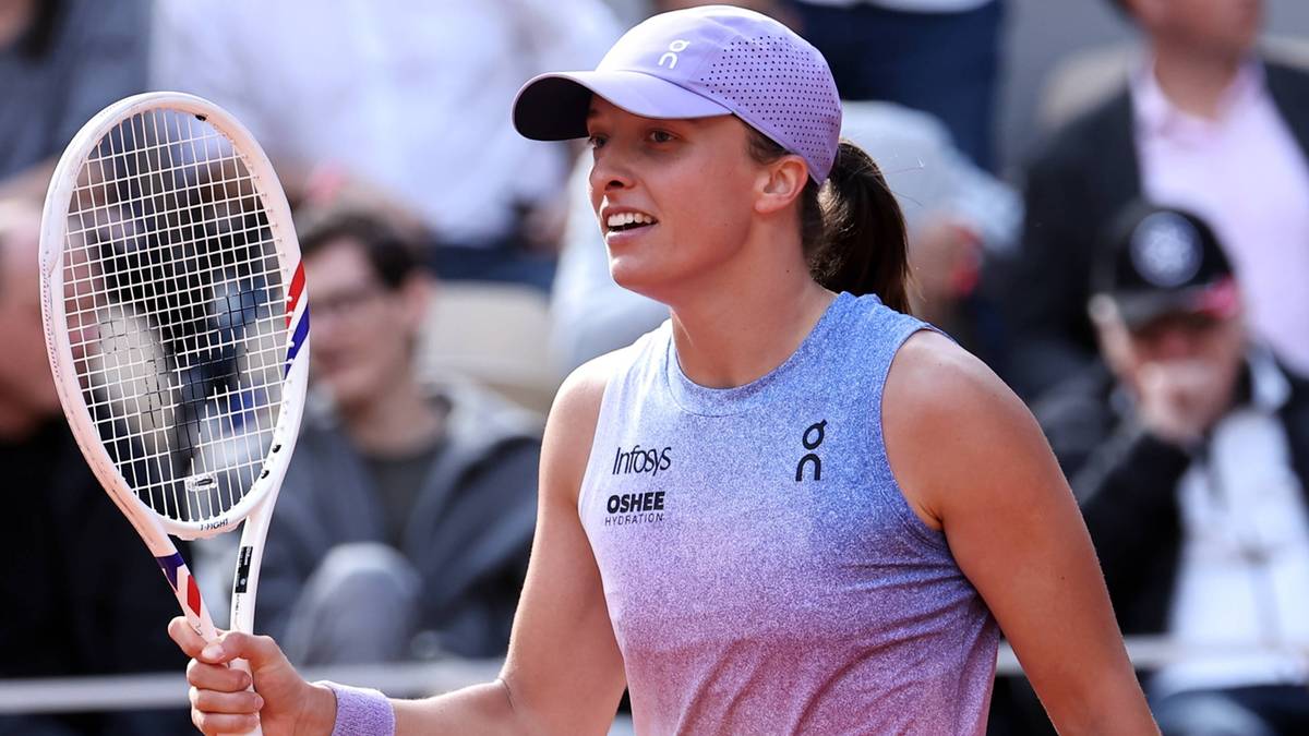 Iga Świątek w czapce i sportowym stroju trzyma rakietę tenisową, gotowa do odbicia piłki.