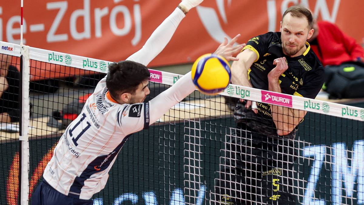 Dw&oacute;ch siatkarzy walczy o piłkę przy siatce podczas meczu.
