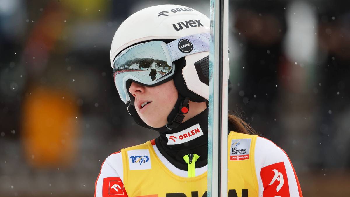 Skoczkini narciarska w kasku i goglach, skupiona przed skokiem.