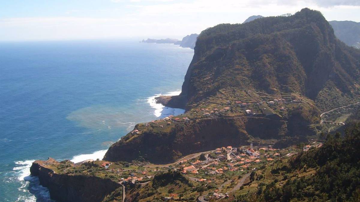 Krajobraz Madery z klifami, oceanem i zabudowaniami na zboczu góry.