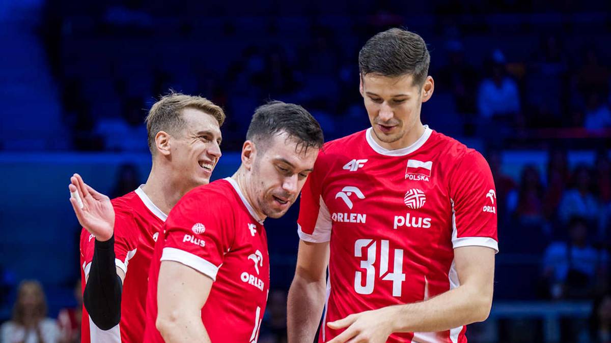 Trzech mężczyzn w czerwonych koszulkach siatkarskich reprezentacji Polski, patrzących w różnych kierunkach.