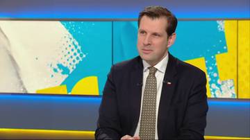 Mężczyzna w garniturze i krawacie, siedzi w studiu telewizyjnym.