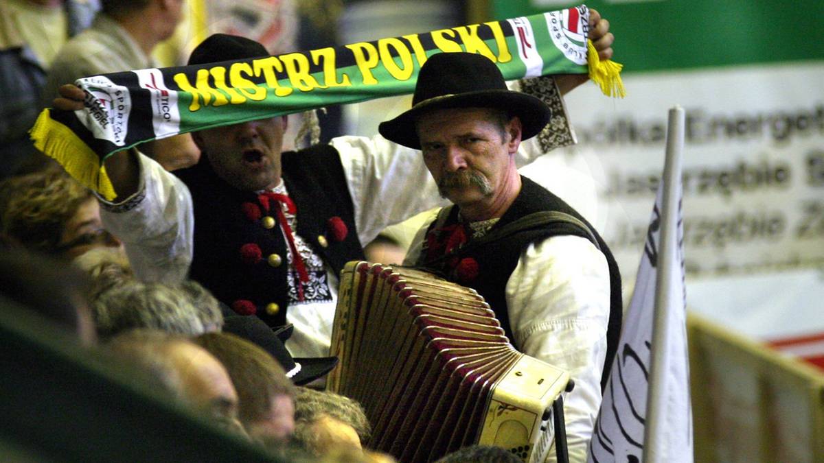 Kibic z szalikiem "Mistrz Polski" i grajek na akordeonie podczas meczu siatk&oacute;wki.