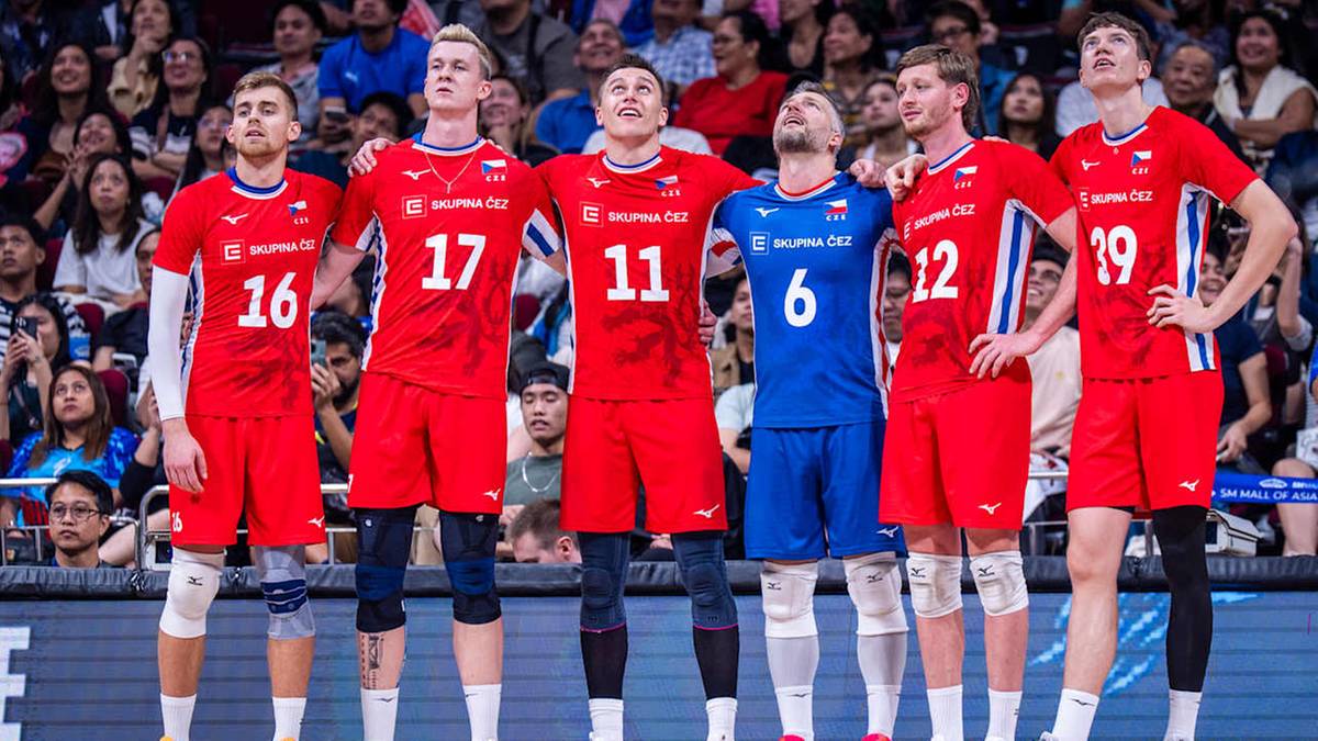 Sześciu męskich siatkarzy w czerwonych strojach sportowych z numerami na plecach, stojących obok siebie i patrzących w różne strony z minami wyrażającymi rozczarowanie.