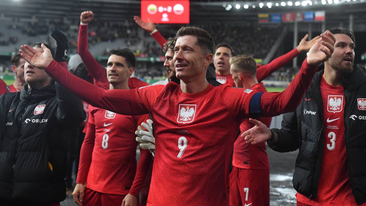 Piłkarze reprezentacji Polski w czerwonych koszulkach świętują zwycięstwo na boisku, z uniesionymi rękami.