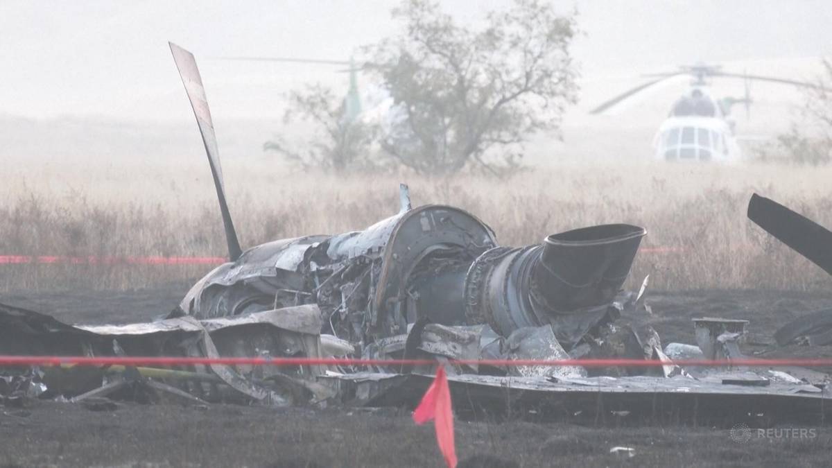 Szczątki rozbitego samolotu C-130 Hercules na ziemi, z helikopterami w tle.