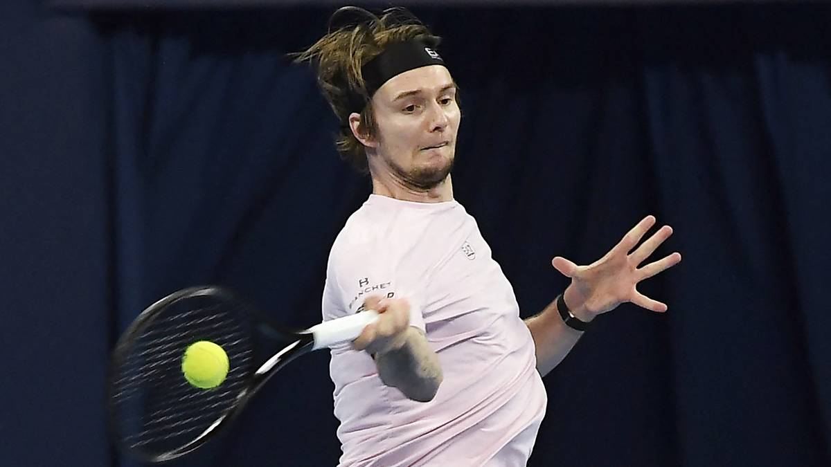 Mężczyzna grający w tenisa, uderza piłkę rakietą.