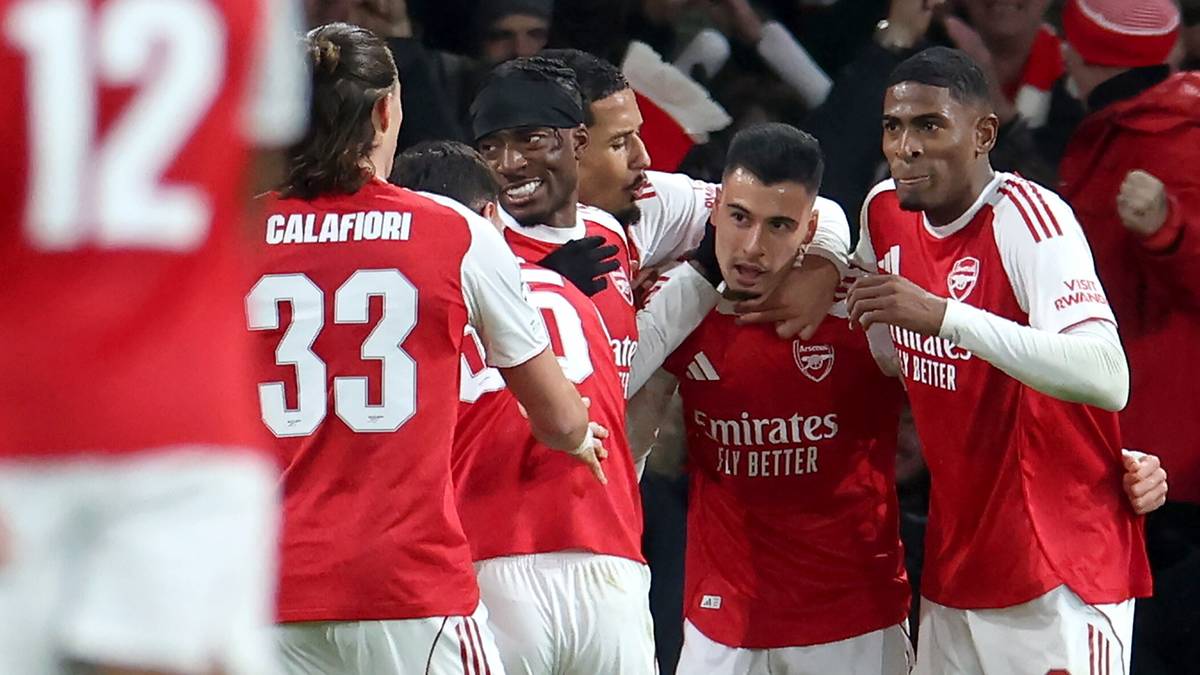 Piłkarze Arsenalu w czerwonych strojach świętują po zdobyciu bramki, jeden z nich jest obejmowany przez kolegę z drużyny.