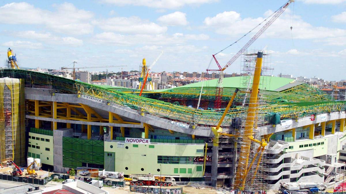 Widok stadionu sportowego w trakcie prac budowlanych z licznymi dźwigami i rusztowaniami.