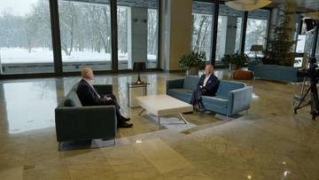 Dw&oacute;ch mężczyzn rozmawia w nowoczesnym wnętrzu z widokiem na zimowy krajobraz.