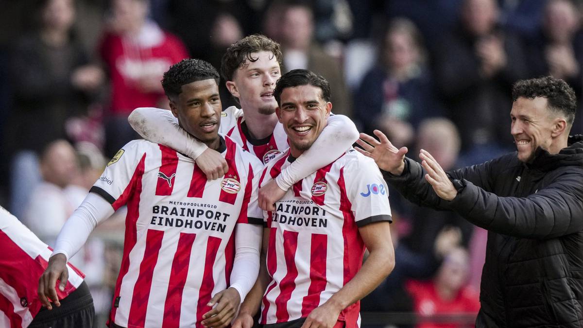 Piłkarze PSV w białych i czerwonych strojach świętują sukces na boisku.